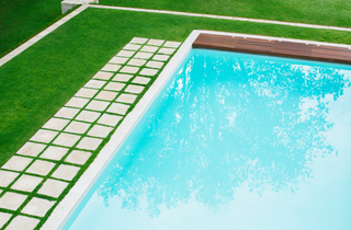 Corner of a sunny swimming pool, no swimmers in sight