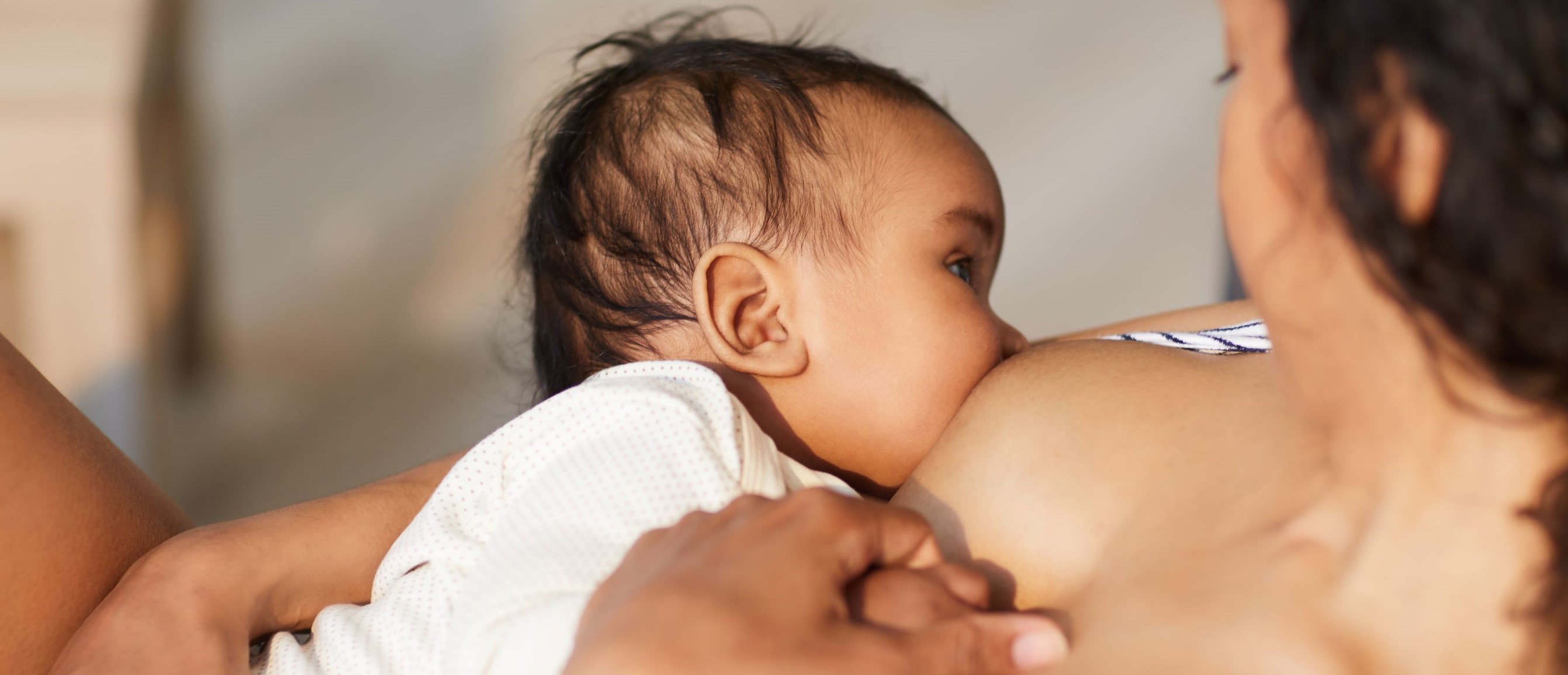 a baby breastfeeding on their mother's chest