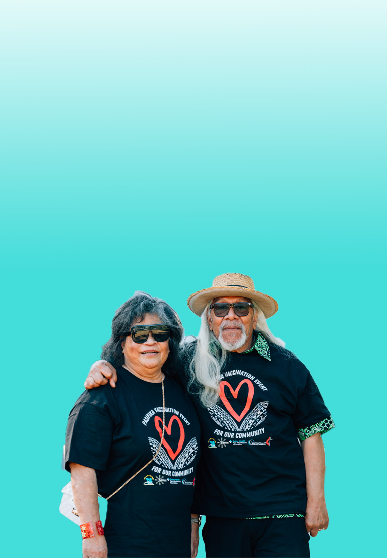 A man and a women pose together. Both are wearing black shirts with red hearts printed on them.