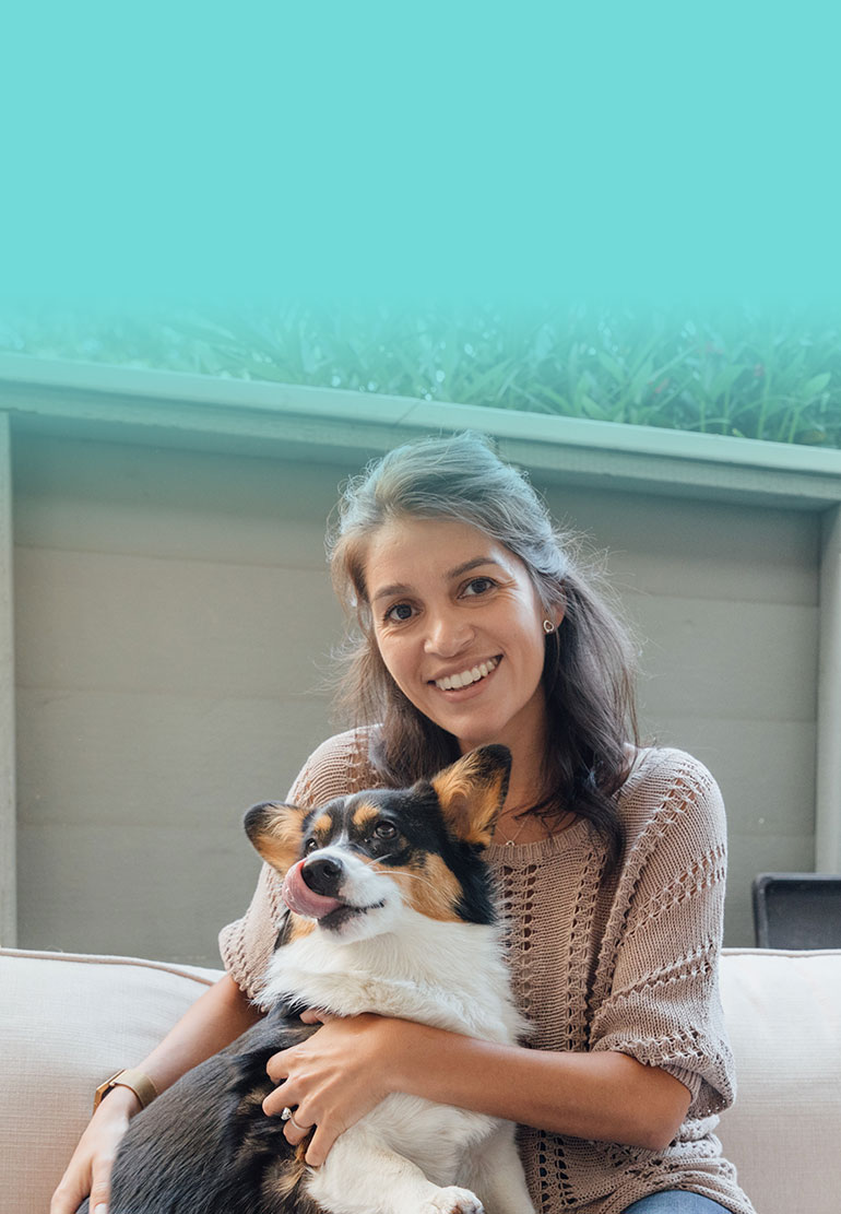 A women smiles while holding a Corgi.