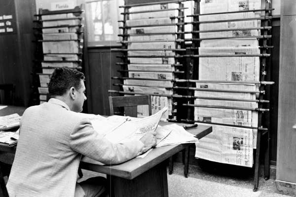 Man reading newspapers in library