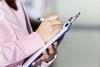 An image showing a woman taking notes on a clipboard