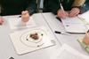 High school students with pens and paper looking at balls of play dough laid out in the shape of an atom