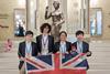 A group of four students wearing medals and holding a Union Jack flag