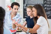 School students examine a molecular structure model. Their teacher is talking with them about the molecular structure