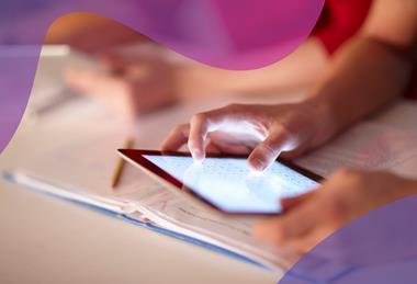 A close-up of a student's hands as they use a tablet to zoom in on a copy of the periodic table