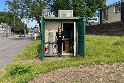 Emma is standing in an outdoor office with equipment inside. 