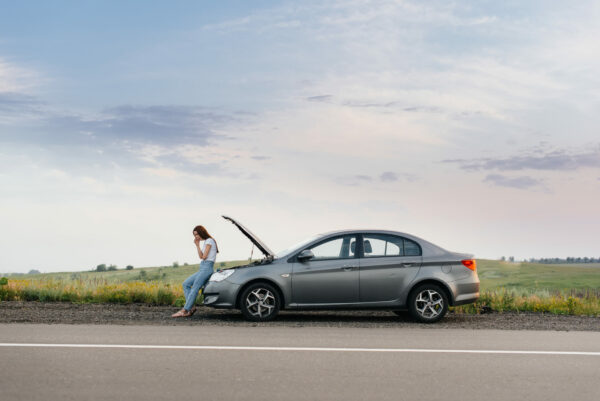 girl with a broken down car on the side of the highway