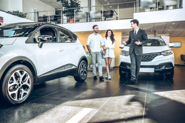 Sales manager helping young couple to choose a new car at a dealership