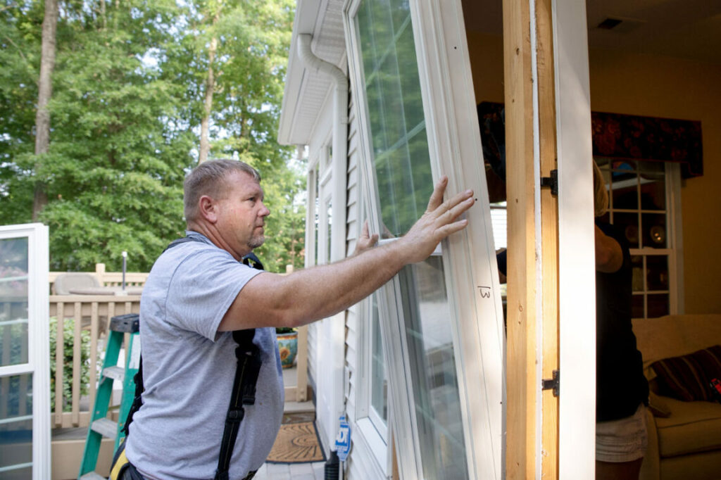 Two Renewal by Andersen window installation contractors installing a new window.