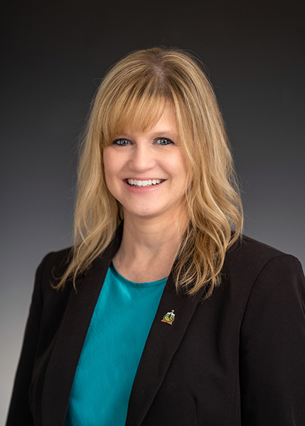 Long blonde-haired woman in green blazer, white blouse