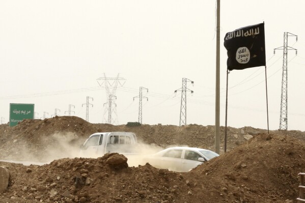 FILE - Islamic State militants pass a checkpoint bearing the group's trademark black flag in the village of Maryam Begg in Kirkuk, 180 miles north of Baghdad, Iraq, Sept. 29, 2014. (AP Photo/Hadi Mizban, File)