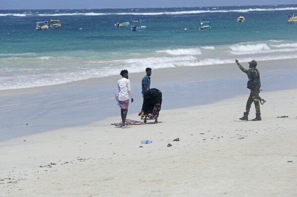 An army officer gesture to people on the beach following an attack in Mogadishu, Somalia, Saturday Aug. 3, 2024. Police in Somalia said Saturday that many people died and several others were wounded in an attack on a beach hotel in the capital, Mogadishu, the previous evening. (AP Photo/Farah Abdi Warsameh)