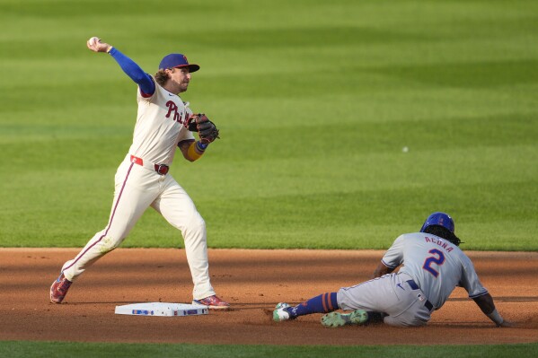 Philadelphia Phillies' Bryson Stott, left, throws to first for a double play as New York Mets' Luisangel Acuna slides during the fourth inning of a baseball game, Saturday, Sept. 14, 2024, in Philadelphia. (AP Photo/Derik Hamilton)