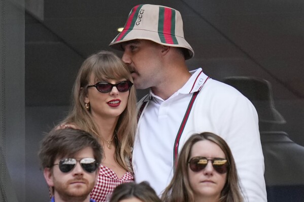 Taylor Swift, left, and Travis Kielce watch play between Jannik Sinner, of Italy, and Taylor Fritz, of the United States, during the men's singles final of the U.S. Open tennis championships, Sunday, Sept. 8, 2024, in New York. (AP Photo/Kirsty Wigglesworth)