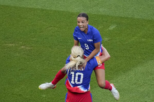 Mallory Swanson, of the United States, up, celebrates with Lindsey Horan, of the United States, after scoring her side's first goal during the women's soccer gold medal match between Brazil and the United States at the Parc des Princes during the 2024 Summer Olympics, Saturday, Aug. 10, 2024, in Paris, France. (AP Photo/Vadim Ghirda)