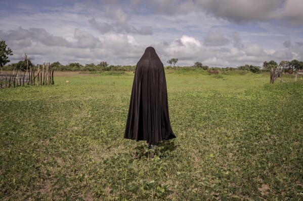 Metta, a survivor of female genital mutilation, poses for a photograph in the village of Sintet, in Gambia, Friday, July. 26, 2024. When Metta, a mother of six from rural Gambia, heard that lawmakers were considering reversing the country's ban on female genital cutting, a centuries-old practice she underwent as a child and now fiercely opposes, she was determined that her voice be heard. She packed her bag and boarded a bus to the capital, Banjul, to join scores of women protesting in front of the parliament in this largely Muslim nation of less than 3 million people in West Africa. (AP Photo/Annika Hammerschlag)