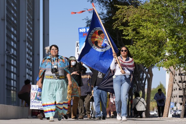 Zoe Perry, left, and Loveena Watahomiegie, right, as they join other members of the Hualapai Tribe while marching in front of U.S. District Court as they gathered to try to persuade a federal judge to extend a temporary ban on exploratory drilling for a lithium project near tribal lands Tuesday, Sept. 17, 2024, in Phoenix. (AP Photo/Ross D. Franklin)