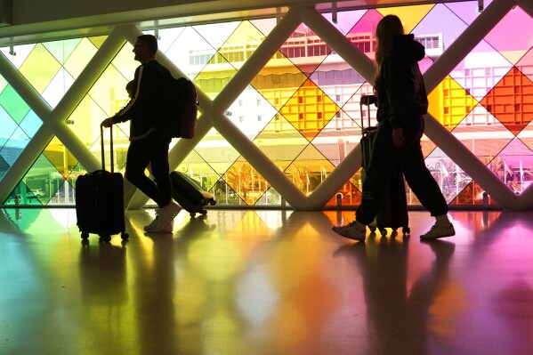 FILE - Travelers walk through Miami International Airport on Nov. 22, 2023, in Miami. Experts say paying down debt and saving for a rainy day remain the safest things to do with your tax refund. Some consumers are spending the money, however, on things like travel and patio furniture.(AP Photo/Lynne Sladky, File)