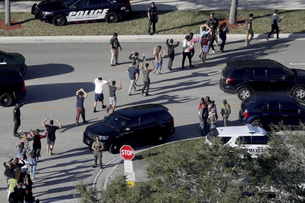 FILE - Students hold their hands in the air as they are evacuated by police from Marjory Stoneman Douglas High School in Parkland, Fla., after a shooter opened fire on the campus on Feb. 14, 2018. Seventeen students and staff were killed in the attack. (Mike Stocker/South Florida Sun-Sentinel via AP)