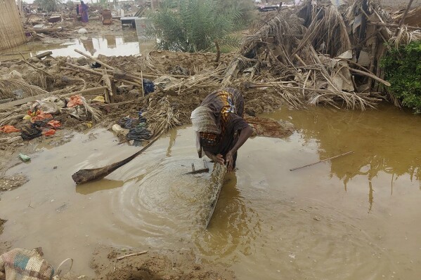 A woman sorts through floodwaters near her damaged home near the city of Abu Hamdan in Northern Sudan on Aug. 7, 2024. (AP Photo/ Samira Hassan)