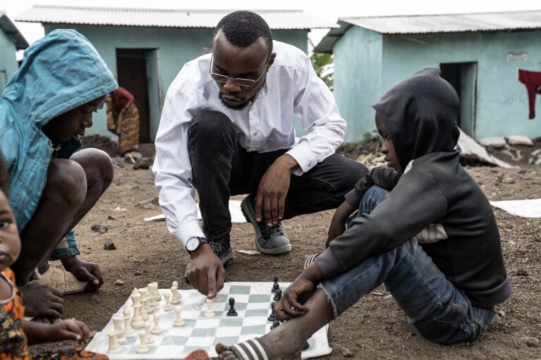 Akili Bashige, president of Soga Chess, plays a chess game with children at 'The Soga Chess Club' of the internally displaced persons camp in Kanyaruchinya, Democratic Republic of Congo, Monday, July 29, 2024. (AP Photo/Moses Sawasawa)