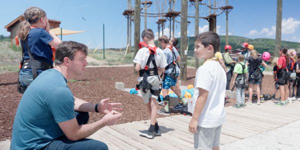 NAC ceo willie ford talking with a participant in front of the high ropes challenge course.