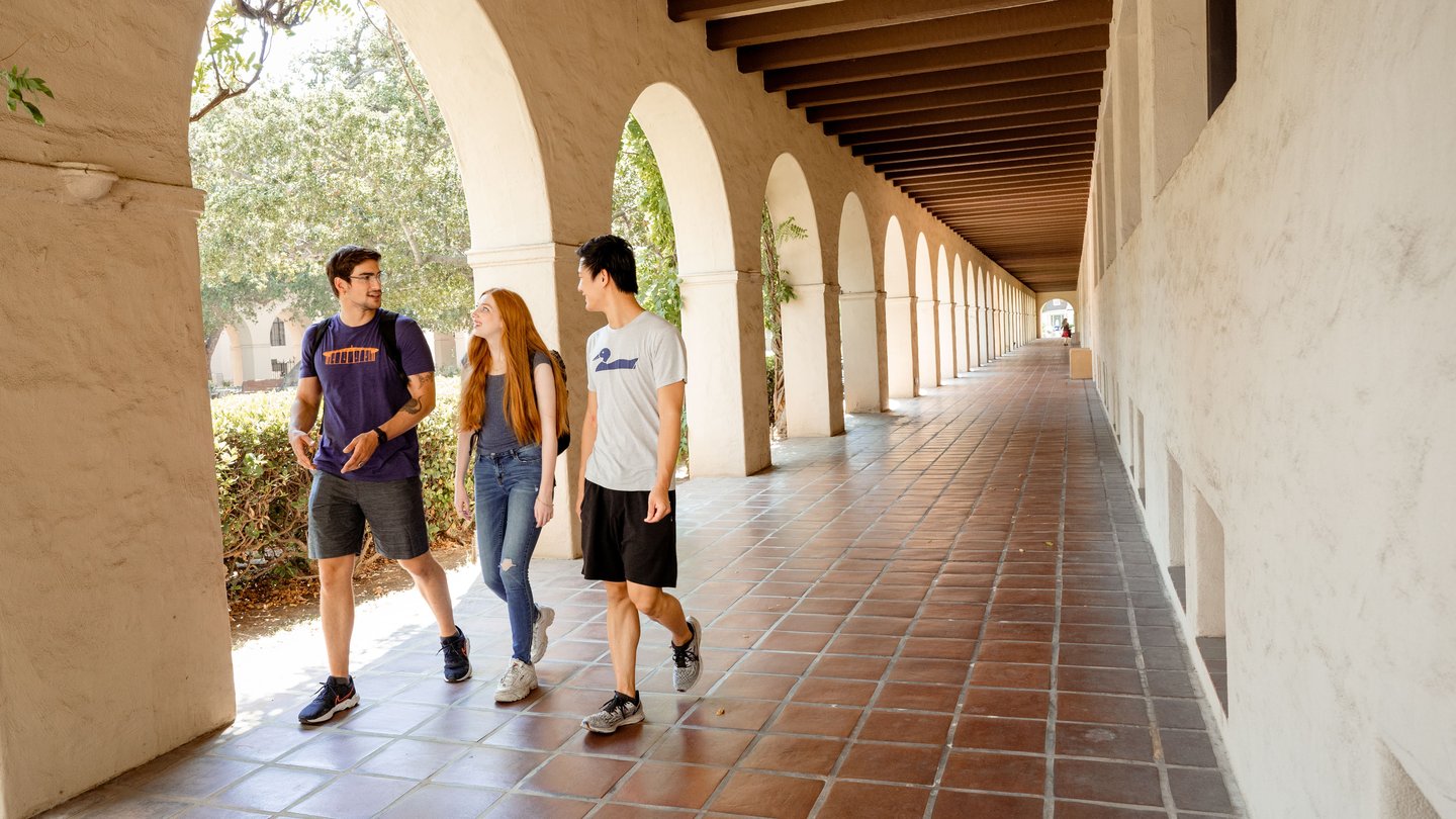 Three students walking outside of campus