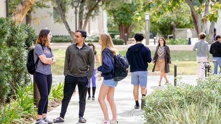 three students talking in a busy walkway