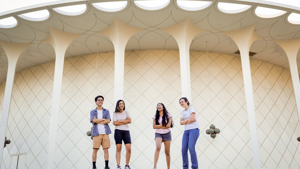 Four students standing outside of campus