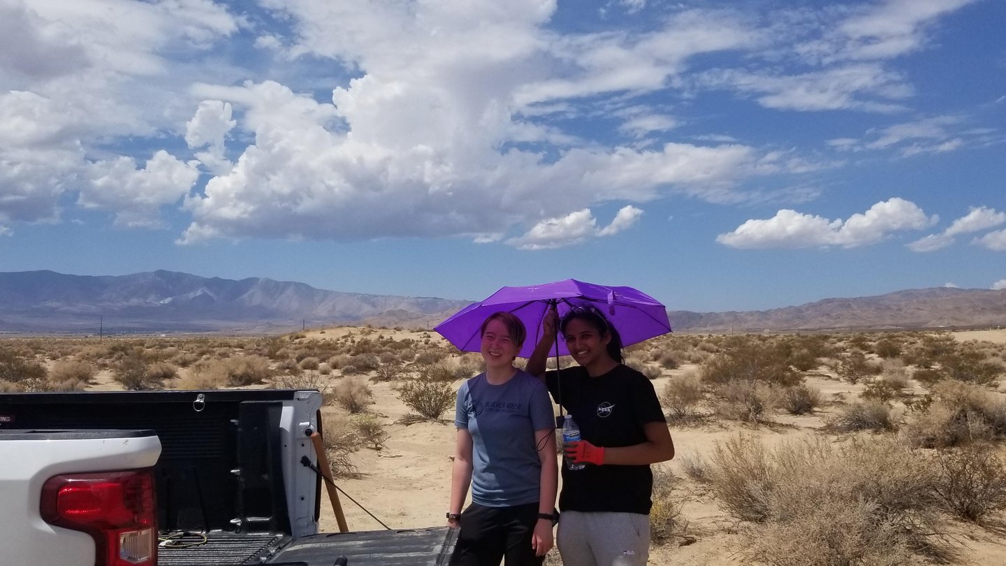 Students with purple umbrella in the desert