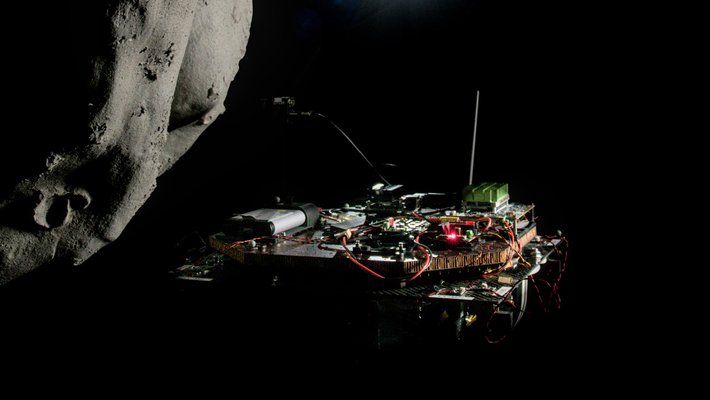 A model spacecraft, on the right, is shown approaching an asteroid on the left, with dim starshine in the center of the image.