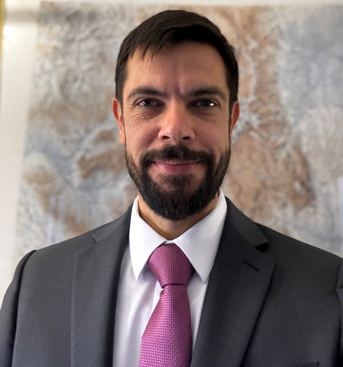 Michael Cunningham, Director, Colorado Division of Reclamation, Mining and Safety. He is wearing a gray suit, with a purple tie with a map of Colorado behind him.