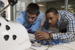 Two men working on a device with circuits.