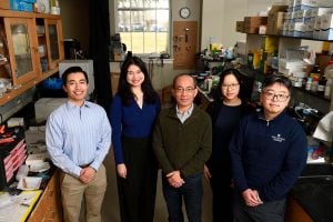 Jeff Wang, posing for a photo in his lab with 4 students.