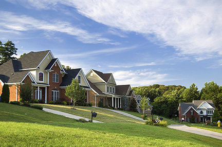 a sunny neighborhood with a blue sky, green grass, and houses