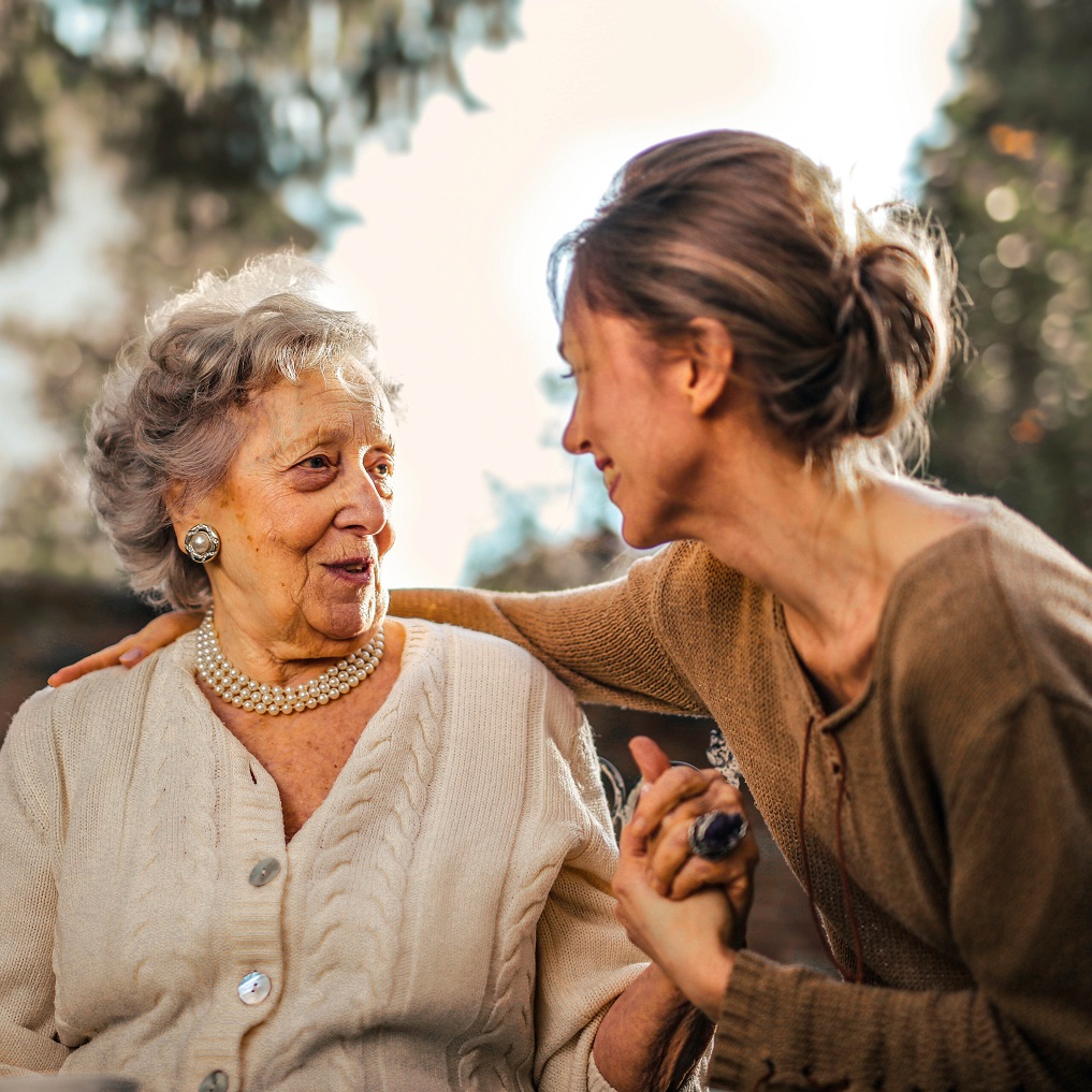 Image of a senior woman grasping the hand of a younger woman