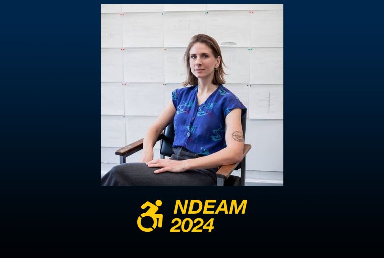 A white woman with chin length hair sits in a chair looking at the camera. She has a blue short sleeved shirt on and dark pants. Behind her are many drawings pinned to a wall. NDEAM 2024 logo.