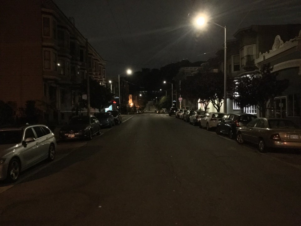 Intersection of Frederick and Downey streets at night, looking eastward, everything is dark except the aforemention things at Frederick and Ashbury, the trees of Buena Vista Park are very dark, outlined by the gray sky above them.