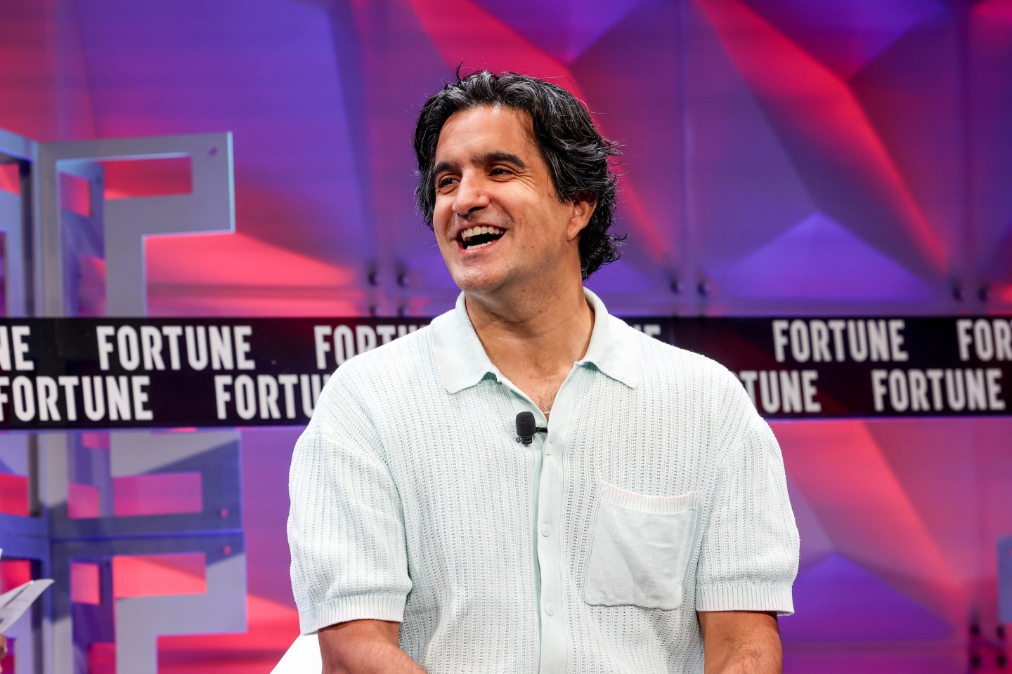 man wearing polo shirt sitting onstage