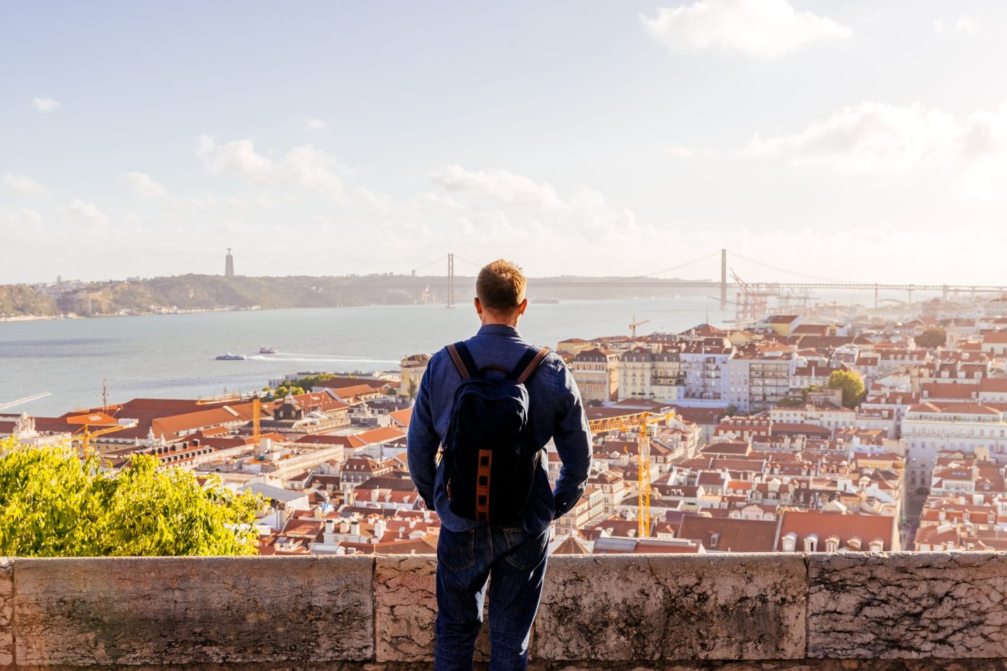 Rear view of a man looking at Lisbon skyline at sunset from above, Lisbon, Portugal