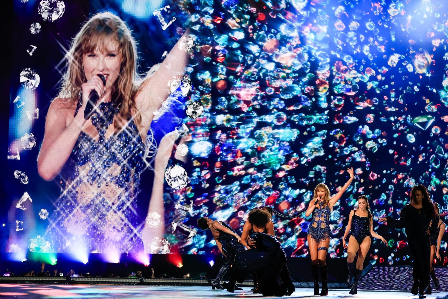 taylor swift singing on a stage with side dancers