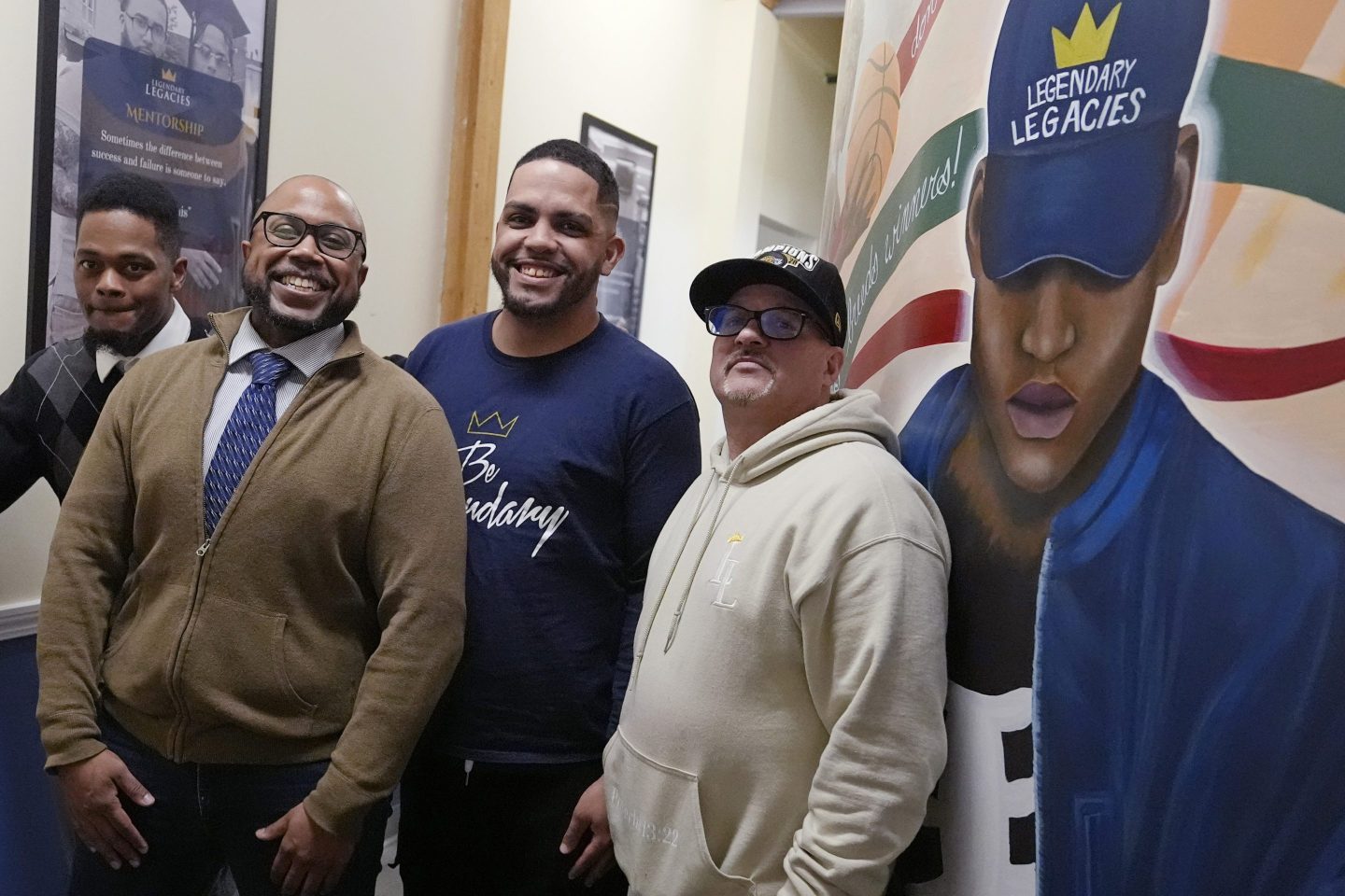 men at a nonprofit pose next to mural