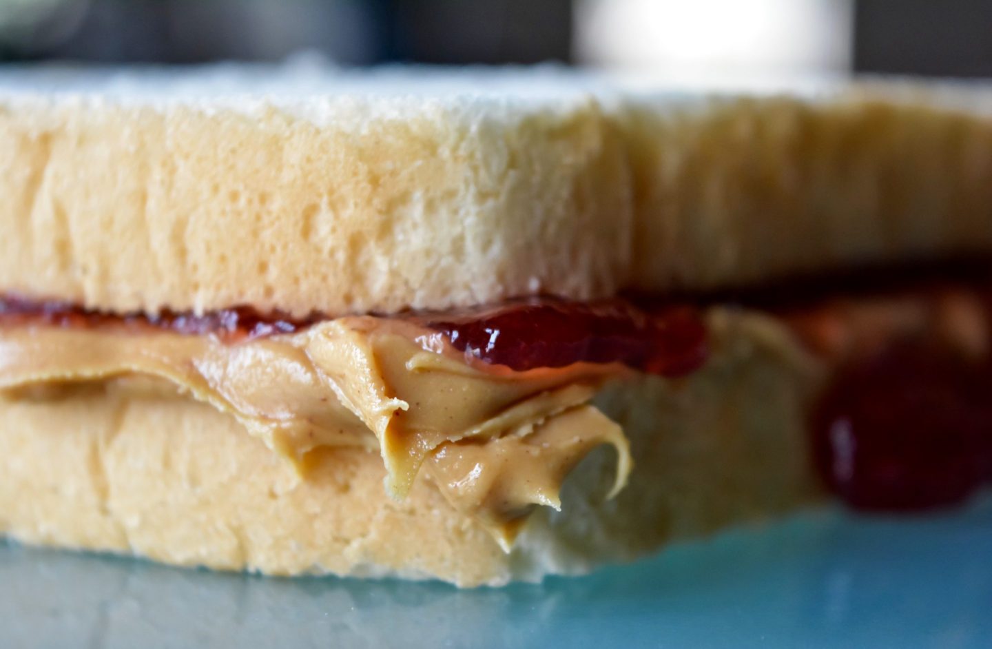 Two slices of bread with overflowing peanut butter and strawberry jelly.