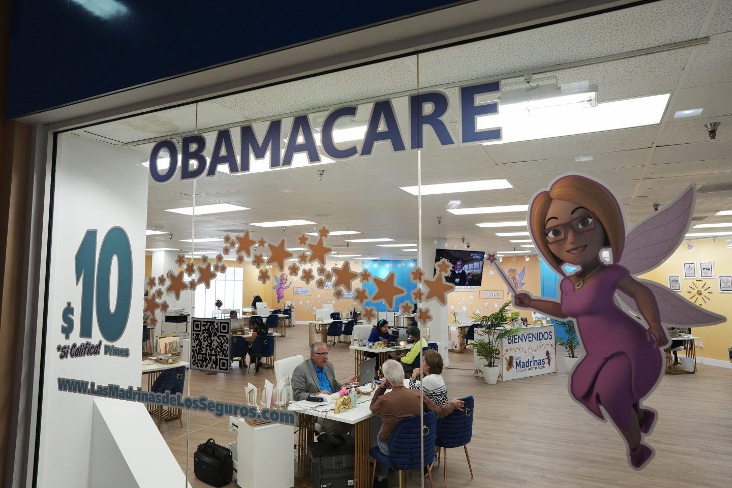 FILE &#8211; An insurance agent talks with clients inside the main location of Las Madrinas de los Seguros, Spanish for &#8220;The Godmothers of Insurance,&#8221; at a shopping center in Miami, on Dec. 5, 2023. Roughly 100,000 immigrants who were brought to the U.S. are expected to enroll in the Affordable Care Act&#8217;s health insurance next year under a new directive the Biden administration released Friday, May 3, 2024. (AP Photo/Rebecca Blackwell, File)