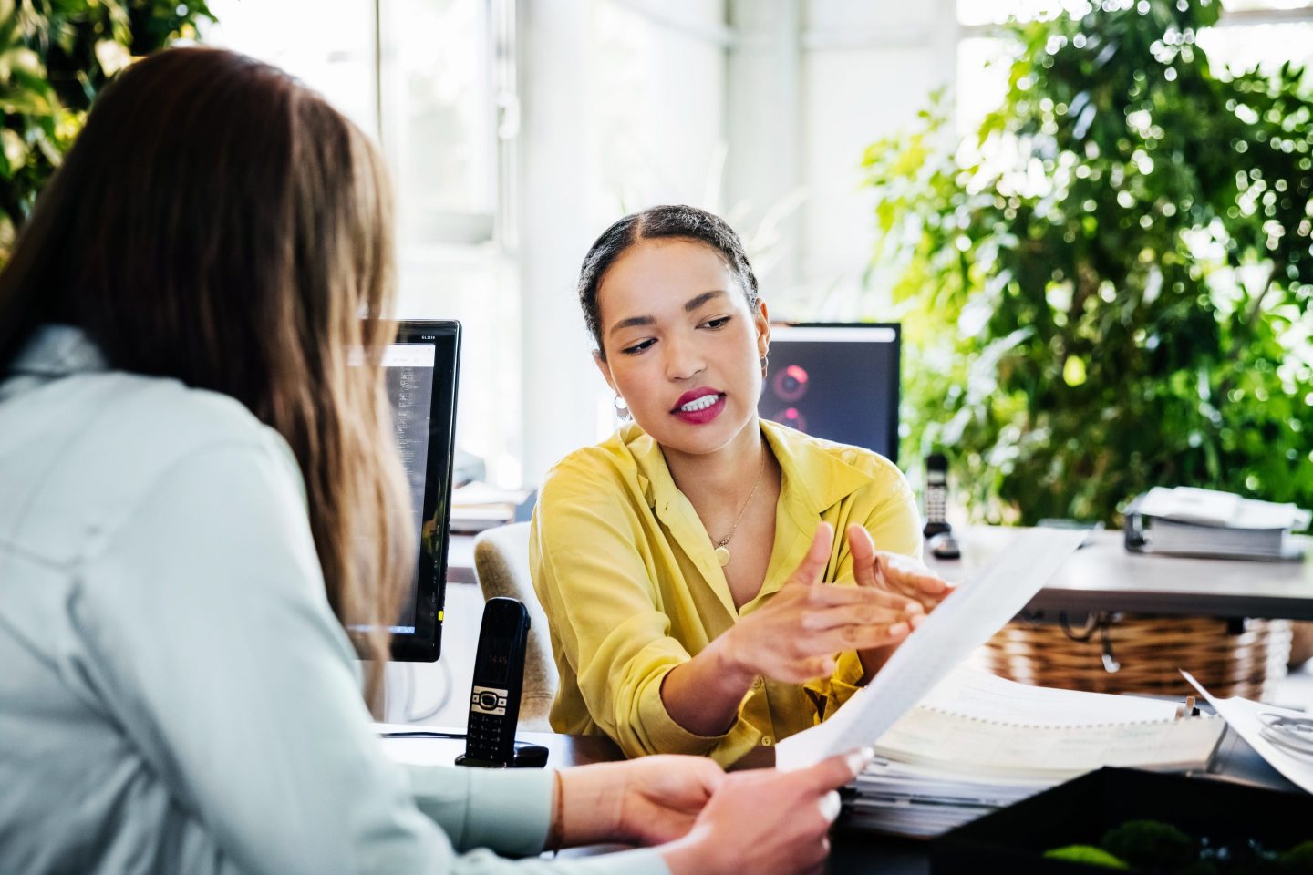 Woman Looking At Paperwork With Office Colleague.