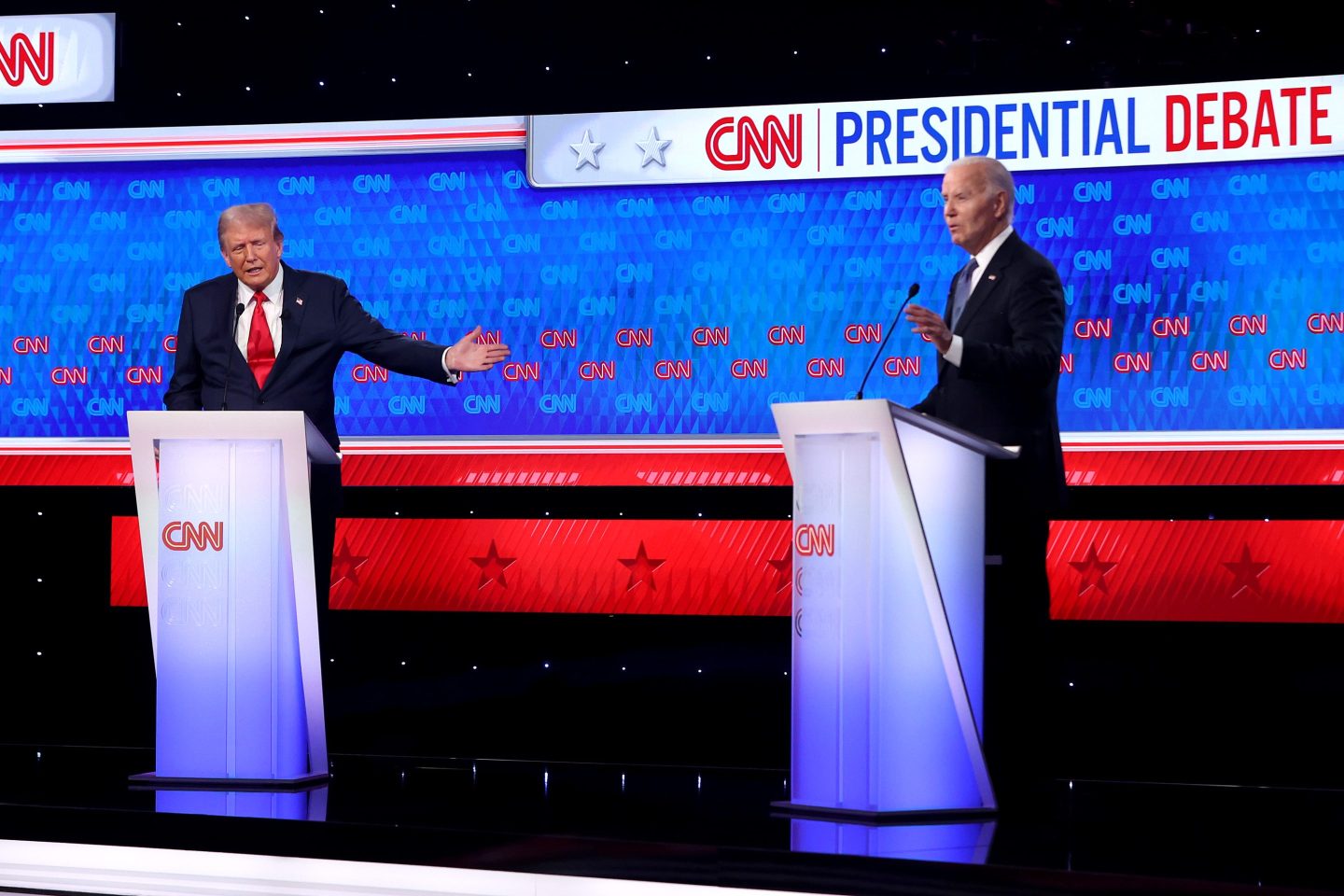 Former President Donald Trump and President Joe Biden stand on a CNN stage behind podiums.