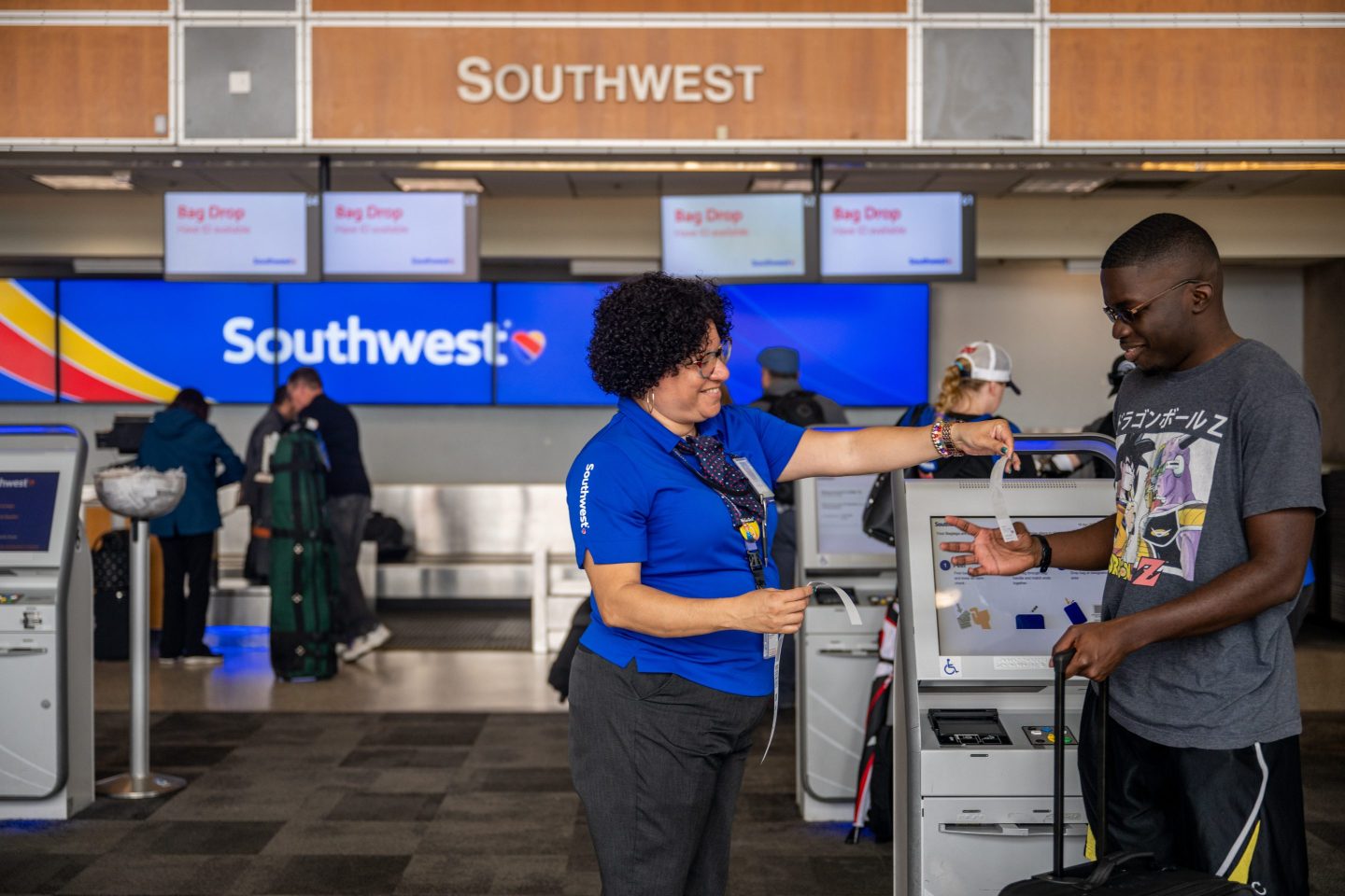 A Southwest Airlines employee assists a passenger during their check-in at Southwest airport kiosk