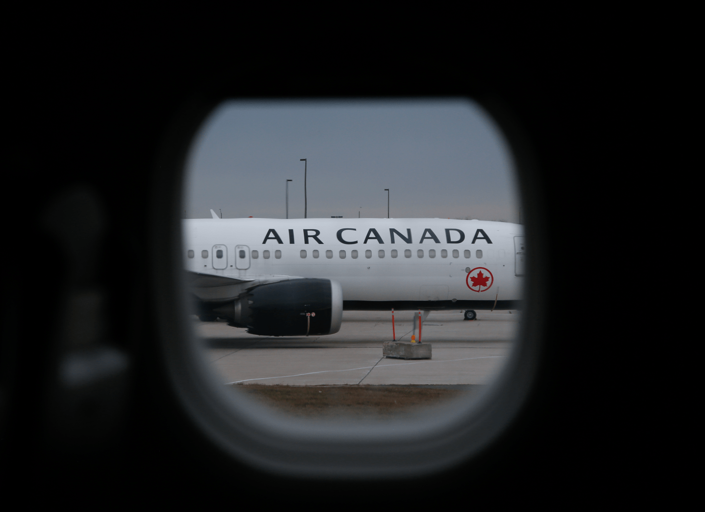 View of an Air Canada plane on the tarmac through a plane window