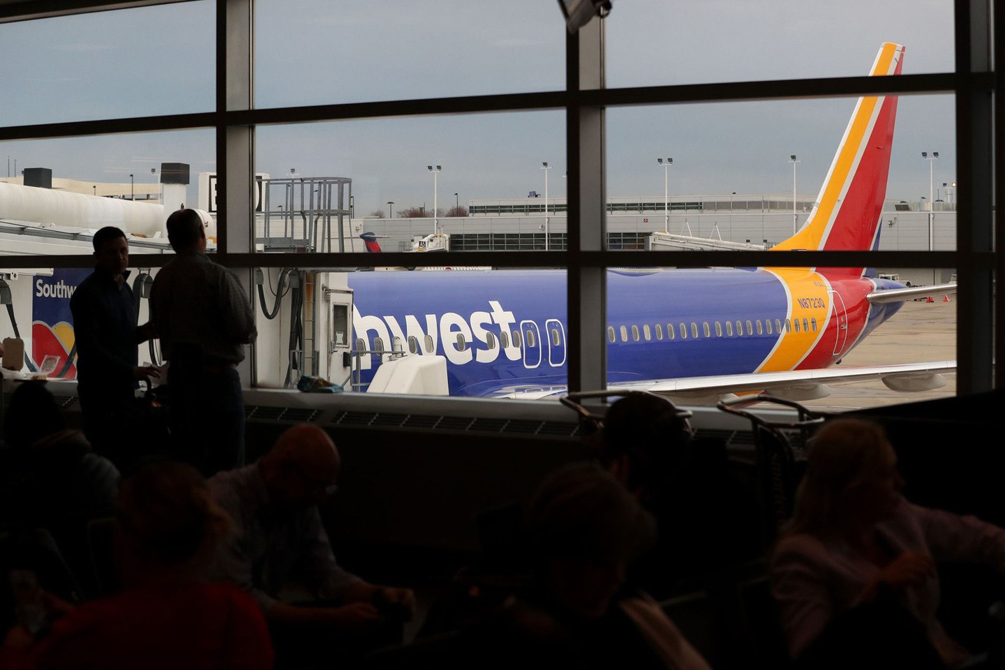 Two people look out at a Southwest Airlines Boeing 737 Max 8 airliner at Gate B20 at Midway Airport in Chicago.